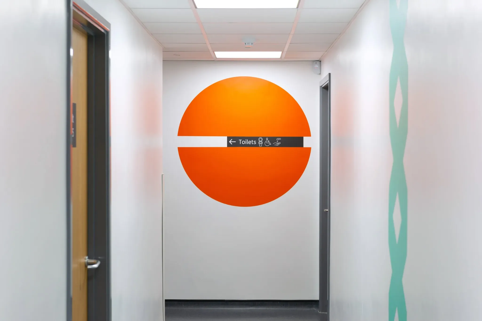 Orange circular landmark incorporating a toilet direction sign