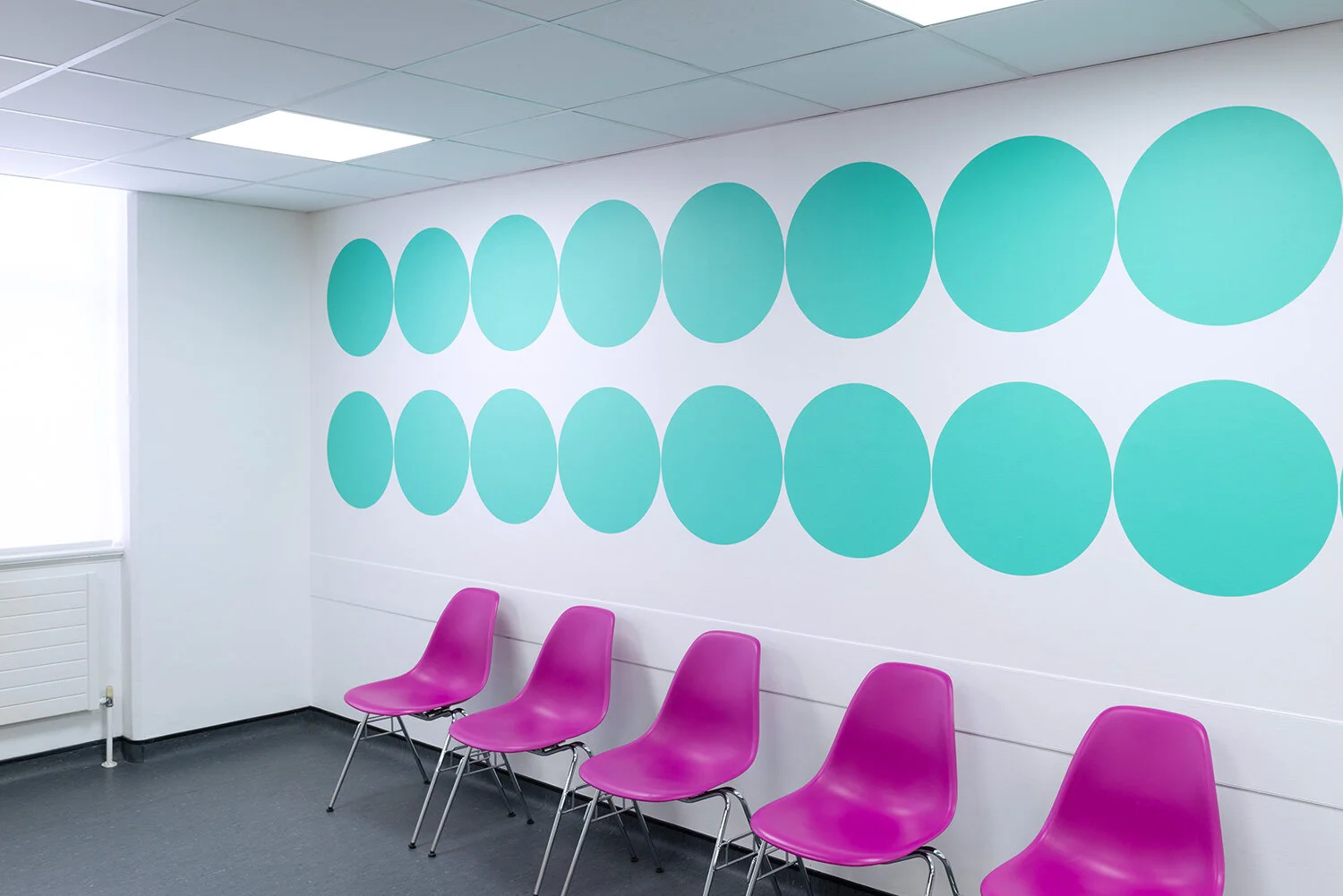 Green circular pattern and pink chairs in a waiting area
