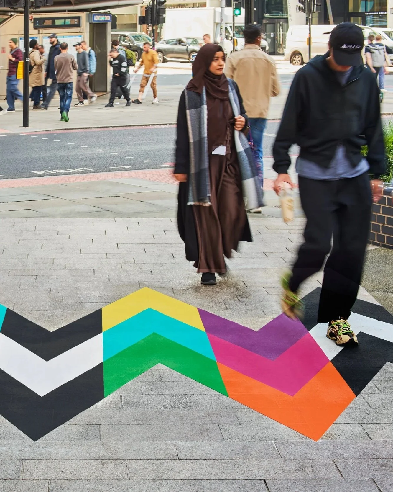 Pedestrians moving across the geometric Intersection artwork