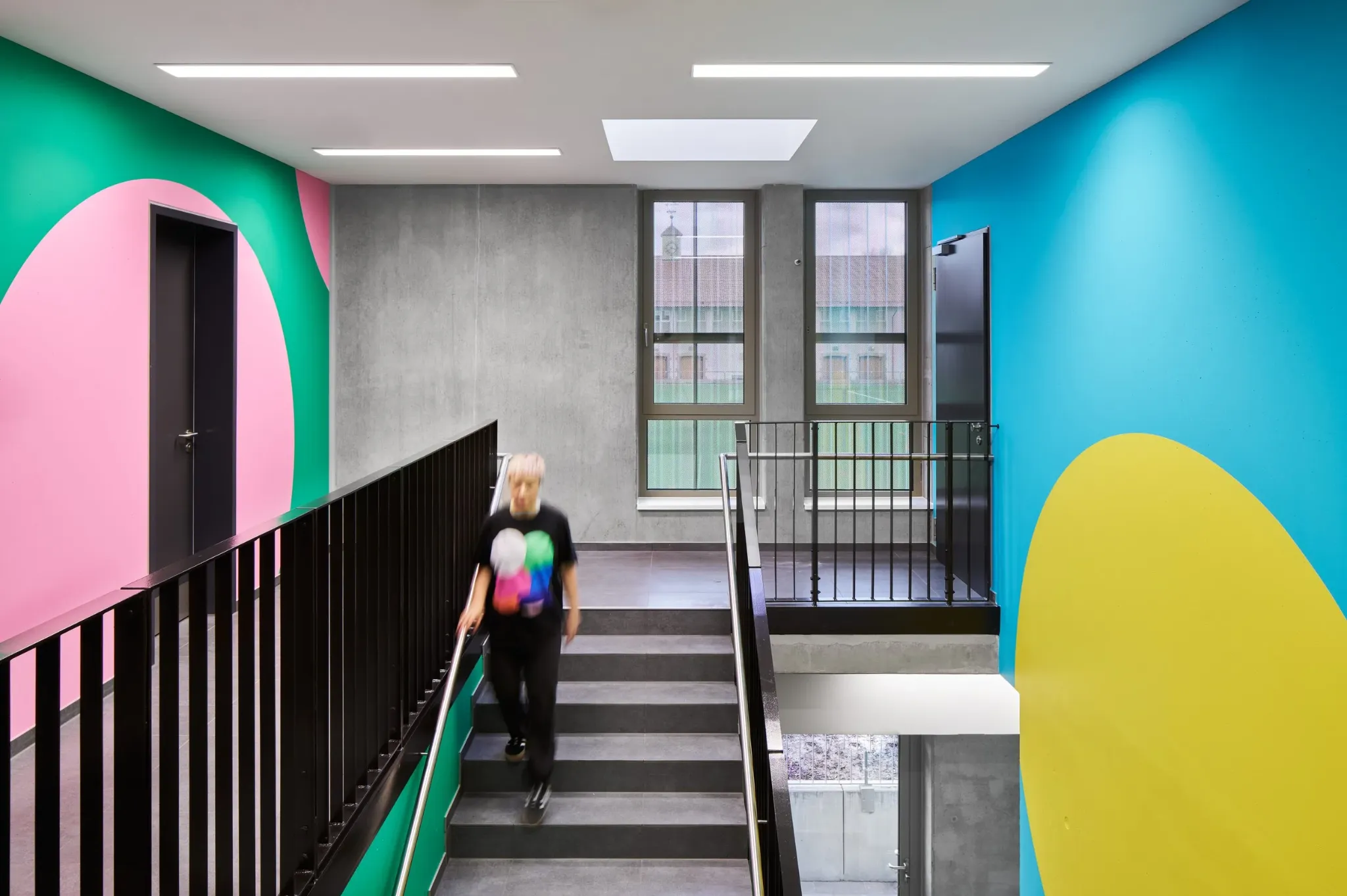 Green, blue, pink and yellow landmarks in a We Play stairwell