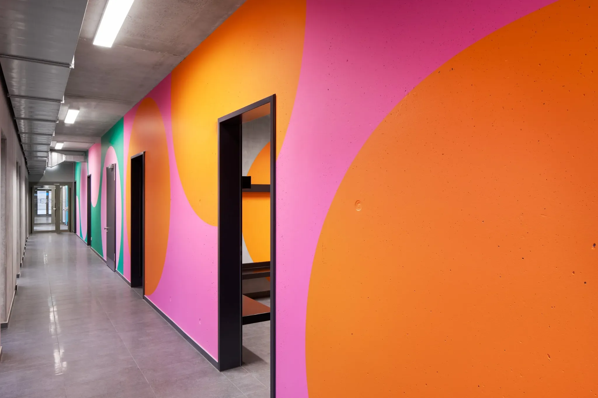 Orange and pink geometric forms leading along a corridor