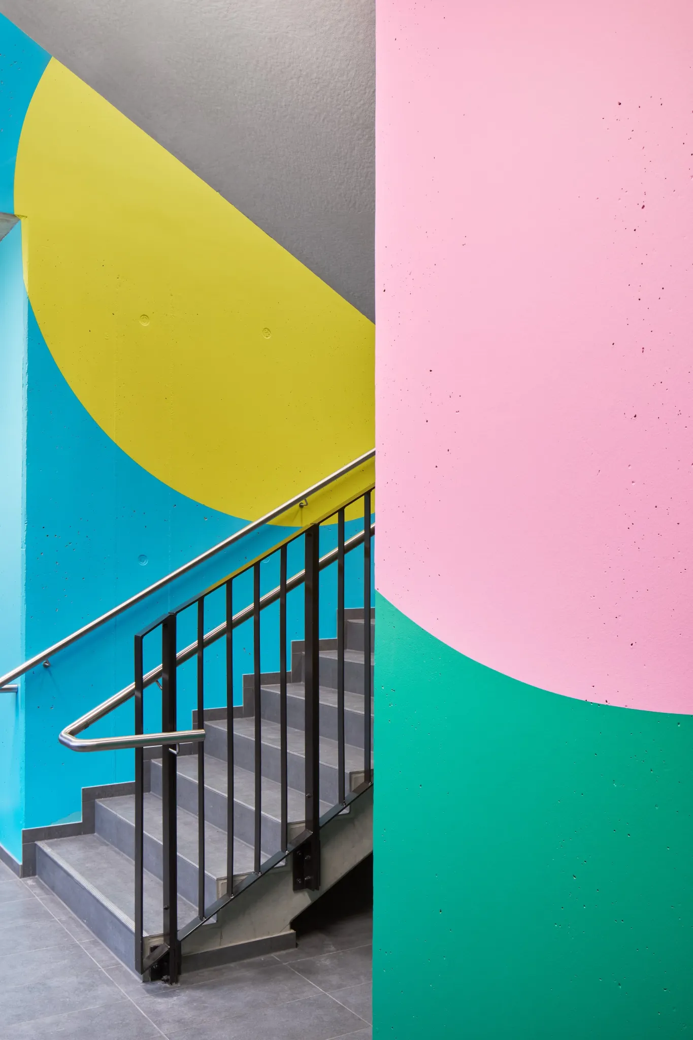 Colourful geometric stairwell artwork in pink, yellow, blue and green