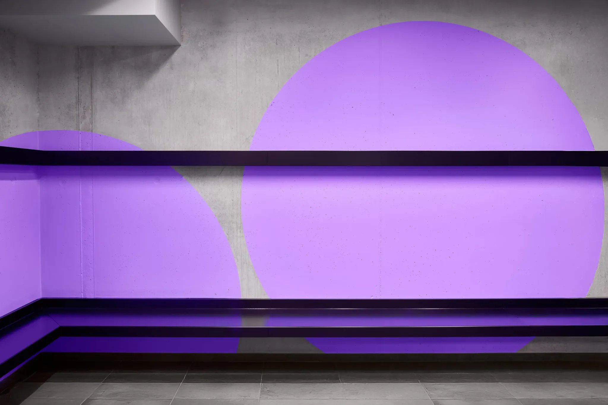 Purple circular forms across concrete walls